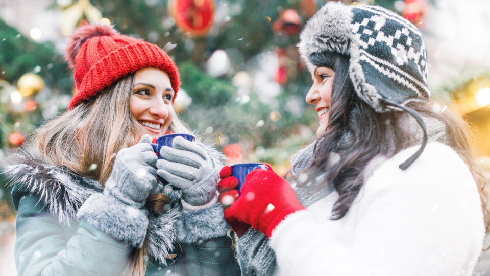 Zwei Frauen trinken Glühwein auf dem Weihnachtmarkt